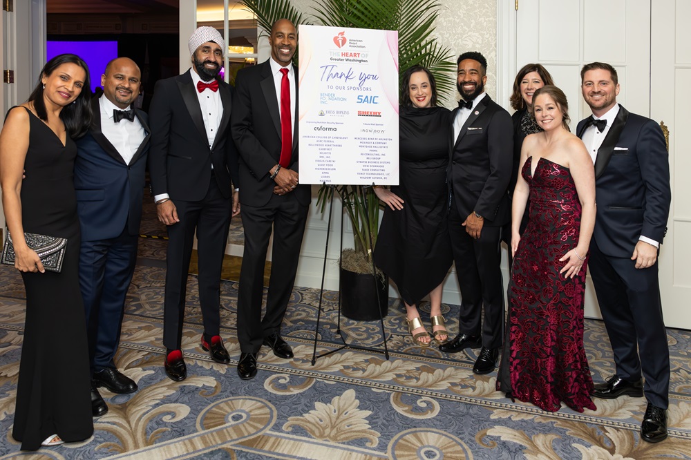 Group of attendees in formal wear standing around a Thank You to Our Sponsors sign